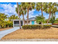 Charming single-story home with a vibrant blue door and well-maintained landscaping at 310 Magnolia Ave, Anna Maria, FL 34216