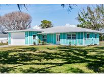 Charming turquoise home with a well-manicured lawn on a sunny day at 400 Dona Dr, Nokomis, FL 34275