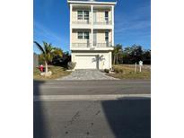 Three-story beige home with garage, multiple balconies and manicured landscaping at 4207 Marina View Way, Cortez, FL 34215