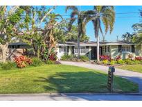 Charming single-story home with a well-manicured lawn, mature landscaping, and a paved driveway at 5211 Carmilfra Dr, Sarasota, FL 34231