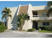 Low-rise condo with a mix of stucco and wood facade, parking lot, and tropical landscaping at 7211 W Country Club N Dr # 135, Sarasota, FL 34243