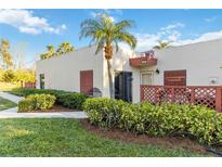 Inviting condo exterior with mature palms, tropical landscaping, and a cozy outdoor seating area at 805 Spring Lakes Blvd # 805, Bradenton, FL 34210