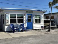 Charming cottage featuring a bright blue door, two chairs on the front patio and well-maintained landscaping at 10315 Cortez W Rd # 12-3, Bradenton, FL 34210