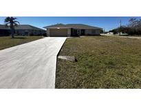 Charming single-story home with a well-manicured lawn and a concrete driveway leading to an attached garage at 2001 Logsdon St, North Port, FL 34287