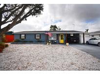 Charming single-story home with a yellow front door, stone landscaping, and a covered carport at 5419 1St W Ave, Bradenton, FL 34209