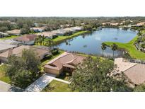 Beautiful aerial view of a home with a red tile roof, nestled next to a serene lake and lush greenery at 6637 Deering Cir, Sarasota, FL 34240