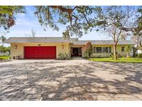 Charming single-story home featuring a red garage door, brick driveway, and lush landscaping at 6640 Peacock Rd, Sarasota, FL 34242