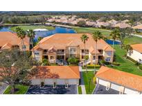 Beautiful building with tile roof situated alongside a golf course, pond and lush tropical landscape at 8414 Wethersfield Run # 102, Lakewood Ranch, FL 34202