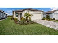 Charming home featuring a well-manicured lawn, an attached garage, and decorative landscaping at 10470 Spring Tide Way, Parrish, FL 34219