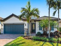 Charming single-story home with a brick driveway, attached garage, and well-maintained landscaping, including tropical palm trees at 12325 Marsh Pointe Rd, Sarasota, FL 34238