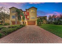 Striking multi-story townhome boasts lush landscaping and a brick-paved driveway leading to attached garages at 1522 3Rd Street E Cir, Palmetto, FL 34221