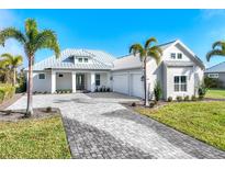 Stunning single-story home boasts lush landscaping, a brick driveway, and a stylish metal roof at 28960 Gin Ln, Punta Gorda, FL 33982