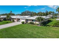 Charming single-story home featuring an attached garage, mature landscaping, and a well-manicured lawn at 3278 Village Green Dr # 1024, Sarasota, FL 34239