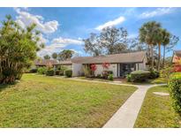 Charming one-story villa with lush landscaping, green lawn, and a welcoming walkway at 3523 Longmeadow # 12, Sarasota, FL 34235