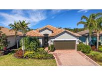 Charming single-story home with a tile roof, manicured landscaping, and a brick paver driveway at 5946 Caspian Tern Dr, Sarasota, FL 34238