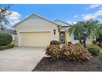 Charming single-story home featuring a manicured lawn, palm tree, and a two-car garage at 1407 Morning Sky Gln, Bradenton, FL 34208