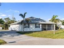 Charming single-story home features a screened lanai, lush lawn, and a concrete driveway at 222 Pine Glen Ct, Englewood, FL 34223