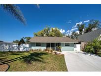 Charming single-story home featuring a well-manicured lawn, light blue exterior, and a long concrete driveway at 470 Leach St, Englewood, FL 34223