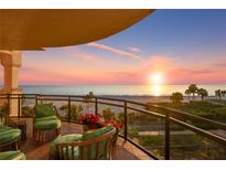 Relaxing balcony with beautiful ocean views, comfortable seating, and vibrant red flowers at sunset at 2141 Gulf Of Mexico Dr Unit # 4, Longboat Key, FL 34228