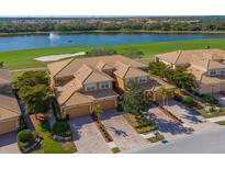 Stunning aerial view of home with barrel tile roof, lush landscaping, water view, and golf course at 322 Winding Brook Ln # 103, Bradenton, FL 34212