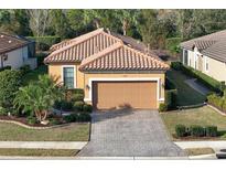Charming single-story home with a tile roof, neatly landscaped yard, and a paver driveway leading to an attached garage at 5020 Savona Run, Bradenton, FL 34211