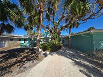 Charming coastal home with lush tropical landscaping and vibrant turquoise exterior paint at 2812 Casey Key Rd, Nokomis, FL 34275