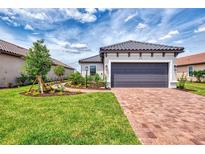 Beautiful single Gathering home with a gray two car garage, paver driveway, and professionally landscaped front yard at 16119 Fortezza Dr, Bradenton, FL 34211