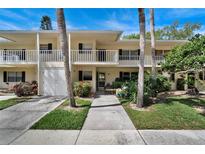 Inviting two-story condo with balconies, a front door entry, lush greenery, and a parking garage at 7860 Palm Aire Ln # 104, Sarasota, FL 34243