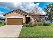 Charming single-story home with a well-manicured lawn, colorful flowerbeds, and a two-car garage at 9828 58Th E St, Parrish, FL 34219