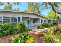 Inviting home with a covered front porch and lush tropical landscaping with a bright blue front door at 4062 S Shade Ave, Sarasota, FL 34231