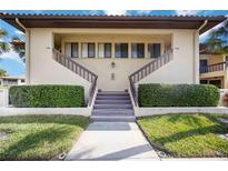 Charming condo with stairs leading to the units, surrounded by green landscaping and palm trees at 5187 Lake Village Dr # 4, Sarasota, FL 34235