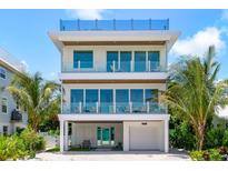 Stunning three-story home with palm trees and multiple balconies at 870 N Shore Dr, Anna Maria, FL 34216