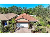 Charming single Gathering home with a tile roof, brick driveway and mature tropical landscaping at 701 Maraviya Blvd, Nokomis, FL 34275