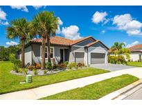 Charming one-story home featuring a tiled roof, a two-car garage, palm trees, and fresh landscaping at 7323 Great Egret Blvd, Sarasota, FL 34241