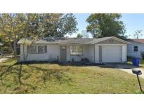 Single-story home featuring an attached garage and a well-kept lawn at 3244 Fairmount Dr, Holiday, FL 34691