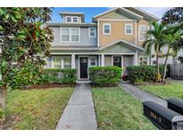 Two-story townhome with gray and tan siding, landscaping, and a walkway at 214 S Westland Ave # 1, Tampa, FL 33606