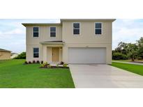 Two-story house with light beige siding, two-car garage, and a well-manicured lawn at 5128 Silver Bell Dr, Port Charlotte, FL 33948