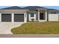 Two-car garage, light-colored house with dark gray doors and trim at 9453 Zorn St, Port Charlotte, FL 33981