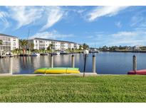 Kayaks on grassy waterfront with boat slips and condo building in background at 3670 Bal Harbor Blvd # 1F, Punta Gorda, FL 33950