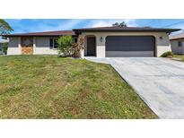 Single-story home with a brown roof, attached garage, and well-maintained lawn at 745 Columbia St, Port Charlotte, FL 33948