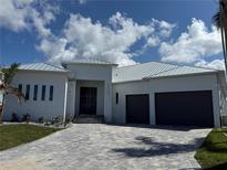 An elegant front exterior with a paved driveway, metal roof, black front doors and a three-car garage at 1426 Mineo Dr, Punta Gorda, FL 33950
