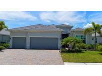 Two-story house with gray exterior, three-car garage, and paver driveway at 25133 Longmeadow Dr, Punta Gorda, FL 33955