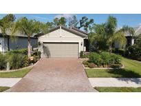 Single-story home with light-colored siding, brick driveway, and lush landscaping at 2555 Brassica Dr, North Port, FL 34289