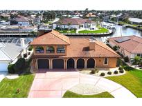 Beautiful two-story waterfront home with a tile roof, arched entryway, and well-manicured lawn at 56 Colony Point Dr, Punta Gorda, FL 33950