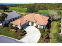 Single-story home with tile roof, landscaped yard, and a golf course view at 13744 Long Lake Ln, Port Charlotte, FL 33953