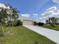Bright home featuring a concrete driveway, well maintained lawn, and blue skies at 3140 Sweet Gum Dr, Punta Gorda, FL 33982
