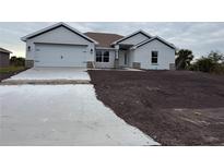 Newly constructed home with two-car garage and unfinished landscaping at 14103 Chambersburg Ave, Port Charlotte, FL 33981