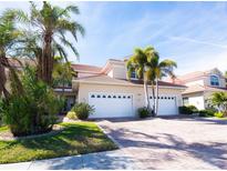 Tan two-story home with white garage doors, landscaping, and palm trees at 143 Tropicana Dr # 1012, Punta Gorda, FL 33950