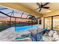 Covered patio with pool and seating area overlooking the water at sunset at 3736 Bal Harbor Blvd, Punta Gorda, FL 33950