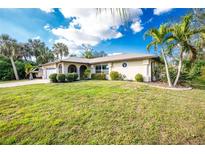 Charming single-story home featuring a well-manicured lawn and tropical landscaping at 1190 Victoria Ave Nw, Port Charlotte, FL 33948